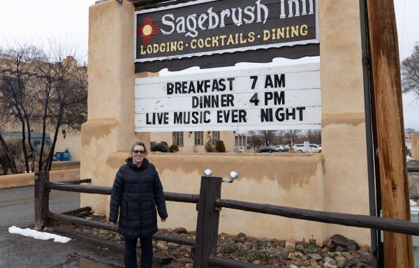 Woman standing in front of Sagebrush Inn sign